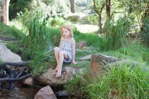 Chica en rocas por río - foto de stock