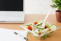 Salada em tigela perto de laptop — Fotografia de Stock