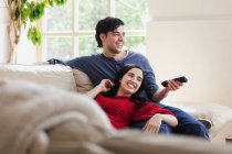 Junges Paar vor dem Fernseher im Wohnzimmer — Stockfoto