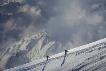 Dos escaladores que ascienden por una ladera nevada, Alpes, Cantón Wallis, Suiza - foto de stock