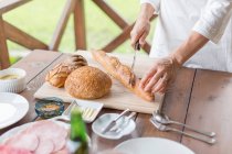 Woman cutting baguette — Stock Photo