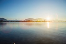 Montanhas e sol sobre lago imóvel — Fotografia de Stock
