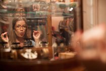 Молода жінка пробує окуляри і витягує обличчя в старовинному магазині — стокове фото
