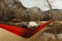 Rear view of woman reclining in red hammock looking out at landscape, Yosemite National Park, California, USA — Fotografia de Stock