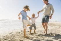 Pai e filhos na praia de mãos dadas — Fotografia de Stock