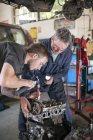 Механики, работающие на автомобильном двигателе в гараже — стоковое фото