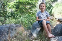 Niño sentado sobre la roca - foto de stock