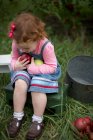 Menina sentada no banco segurando maçãs — Fotografia de Stock