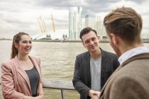 Jeune femme d'affaires et hommes d'affaires en discussion sur le front de mer, Londres, Royaume-Uni — Photo de stock