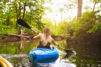 Vue arrière de la jeune femme kayak sur la rivière de la forêt — Photo de stock