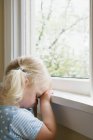 Trauriges kleines Mädchen am Fenster — Stockfoto