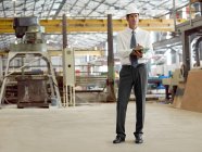 Mature man with clipboard in factory — Stock Photo