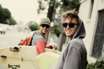 Men carrying surfboards on city street — Stock Photo