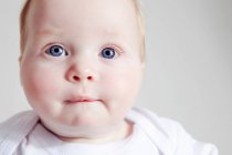 Close up de bebê menina mordendo lábio — Fotografia de Stock