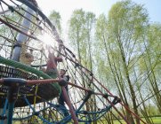 Padre su telaio da arrampicata nel parco giochi con tre figli, vista a basso angolo — Foto stock
