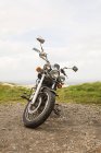 Мотоцикл стоїть на сільській дорозі з травою в похмурий день — стокове фото