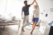 Молода пара в піжамах танцює в спальні — стокове фото