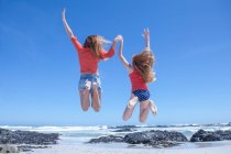 Niños saltando en la costa de Ciudad del Cabo, Sudáfrica - foto de stock