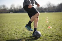 Waist down of young man practicing soccer on playing field — Stock Photo