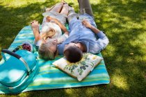 Молодая пара лежит на одеяле для пикника — стоковое фото