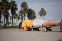 Хлопчик лежить на скейтборді в парку — стокове фото
