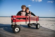 Dos hermanos en el carro en la playa con los brazos alrededor uno del otro - foto de stock