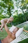 Pai na rede levantando bebê filha — Fotografia de Stock