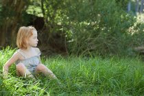 Petite fille assise dans l'herbe — Photo de stock