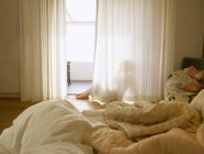 Donna matura seduta dietro le tende della camera da letto — Foto stock