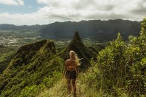 Vista trasera de la mujer en la montaña cubierta de hierba, Oahu, Hawaii, EE.UU. - foto de stock
