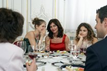 Two women at dinner table whispering — Stock Photo