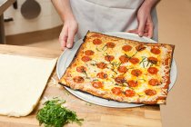 Vista ritagliata del vassoio porta chef maschio con pizza — Foto stock