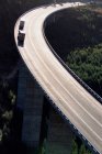 Trucks driving on curvy suspended motorway in sunlight — Stock Photo