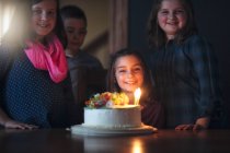Menina com bolo de aniversário cercada por amigos — Fotografia de Stock