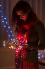 Jeune femme tenant enchevêtrement de lumières de Noël — Photo de stock