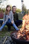 Menina sentada no colo do pai no jardim assistindo fogueira — Fotografia de Stock