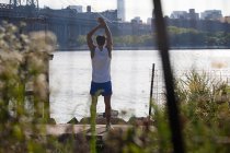 Male runner stretching by river — Stock Photo