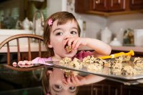 Close up portrait of young female toddler eating currant cakes — Stock Photo
