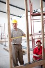 Constructeur et chef de projet mesurant le cadre de construction — Photo de stock