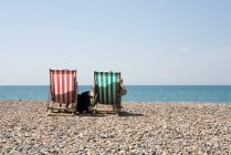 Rear view of deople in deckchairs at sandy beach — Stock Photo