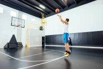 Männlicher Basketballspieler springt in Basketballkorb und wirft Ball — Stockfoto