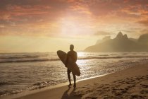 Молода людина, несучи для серфінгу на пляж Іпанема, Ріо-де-Жанейро, Бразилія — стокове фото