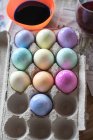 Colored easter eggs in tray and paint in bowl — Stock Photo