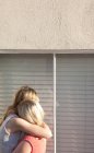 Joven pareja lesbiana abrazando por ventana - foto de stock