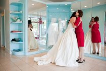 Дочка намагається на весільній сукні, обіймаючи матір — стокове фото