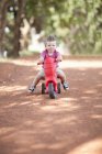 Маленький мальчик катается на игрушке по грунтовой дороге — стоковое фото
