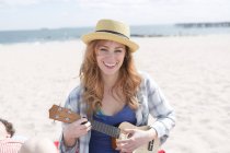 Ritratto di giovane donna sulla spiaggia che suona ukulele — Foto stock