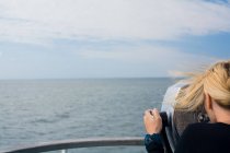 Donna che guarda attraverso il binocolo sul traghetto — Foto stock