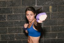 A young brunette woman exercising and boxing punching towards the camera — Stock Photo