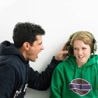Father shouting into boys earphones — Stock Photo